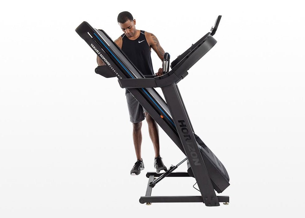 Male pressing the kickstand with his foot on a folded treadmill
