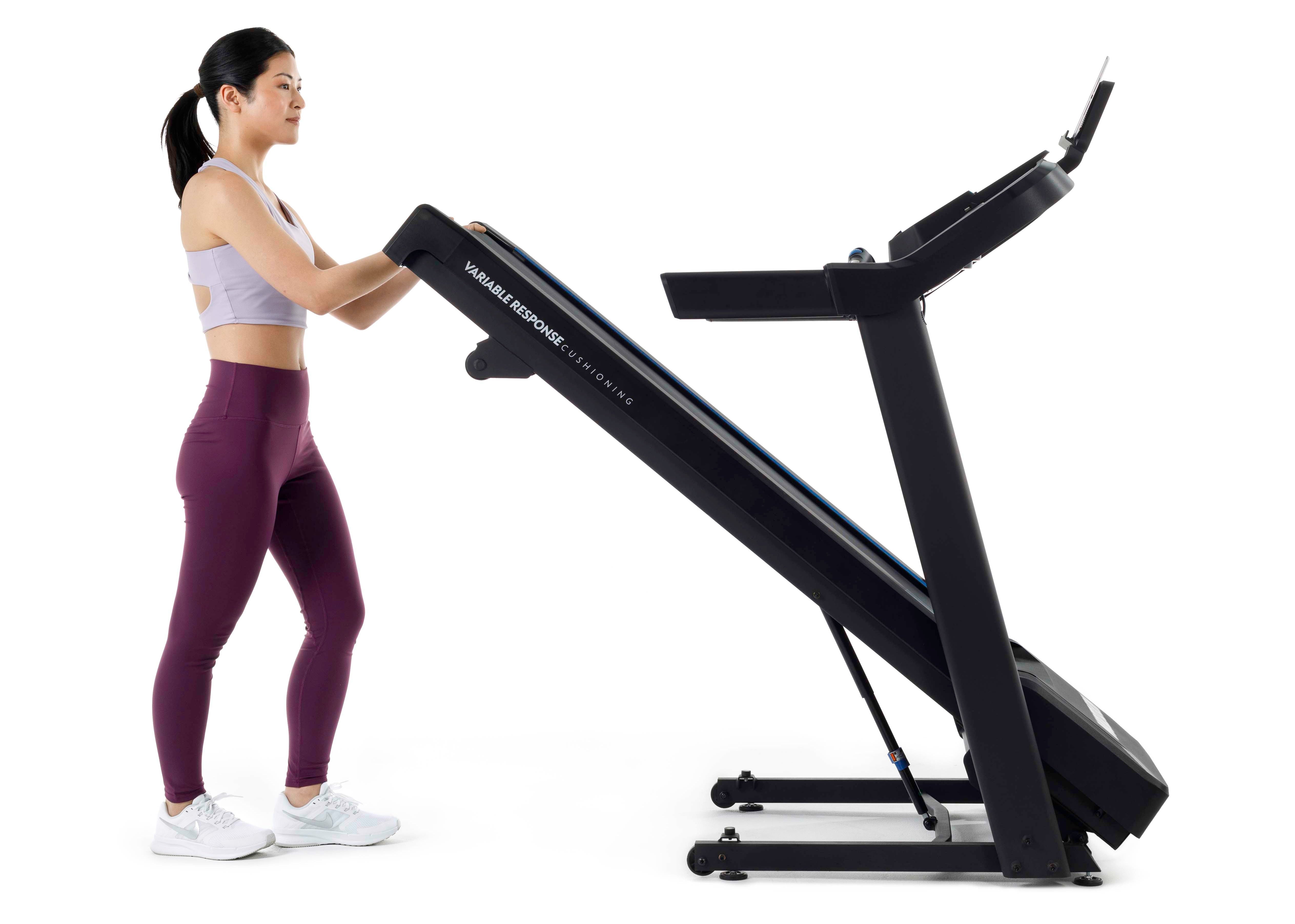 Woman folding a treadmill on a white background